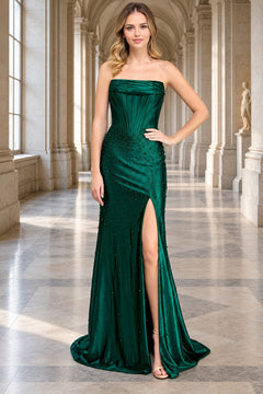A woman wearing an emerald green Amelia Couture 9106 strapless gown with a corset-style bodice, beaded embellishments, a floor-length silhouette, and a high side slit.