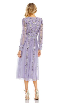 A woman stands facing away, wearing the Knee Length Wedding Guest Dress 9133 by Mac Duggal in lavender with floral embroidery and sheer fabric, paired with metallic high-heeled shoes.