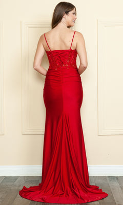A woman faces away in the Sheer-Bodice Long V-Neck Prom Dress 9138, a floor-length red gown with thin straps, fitted bodice, and slight train, radiating timeless sophistication against a beige wall.