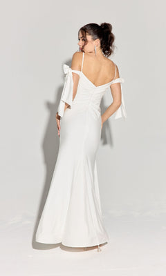 A woman faces away, wearing the Eureka 9181 Shoulder-Ties Long Jersey Prom Dress with bow details and off-shoulder straps, set against a plain light background.