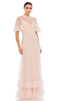 Woman wearing the Mac Duggal 9199 Short Sleeve Beaded Formal Gown, a floor-length pale pink dress featuring sheer short sleeves, floral embellishments, and ruffled tulle accents at the hem and sleeves.
