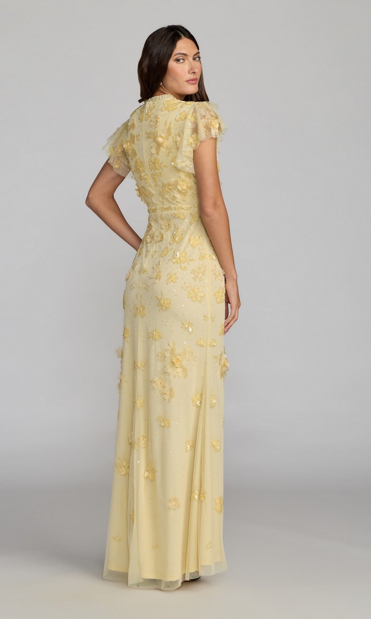 A woman stands against a plain background in the Beaded Periwinkle Formal Gown—Mac Duggal 9206—a floor-length, short-sleeved dress with floral embroidery, offering a graceful choice for a mother of the bride.