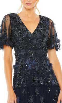 Woman wearing the Mac Duggal 9207 A-Line Wedding Guest Dress in navy blue, featuring short sheer sleeves and floral appliqué, shown from shoulders to mid-thigh.