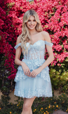 A woman smiles at the camera in front of vibrant pink flowers, wearing the Sequin Sheer Corset Homecoming Dress: Juliet JT920K.