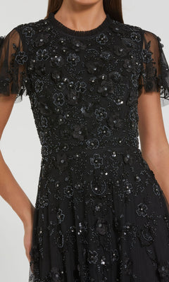 Wearing the Mac Duggal 9212 Floral Midi Wedding-Guest Dress—black with short sheer sleeves, black floral appliqués, and sequins—makes a chic statement for any floral-themed wedding.