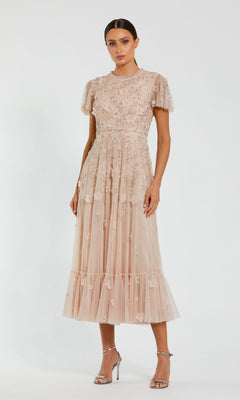 Woman wears the Floral Midi Wedding-Guest Dress: Mac Duggal 9212 in light pink with embroidery and sheer details, paired with silver heels, standing against a white background—the ideal choice for a wedding guest.