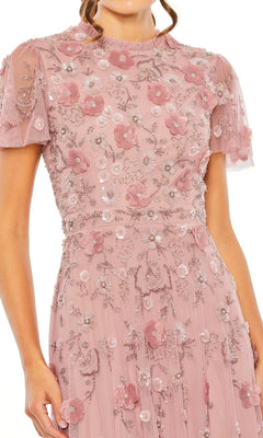 A woman wears the Mac Duggal 9212 Floral Midi Wedding-Guest Dress featuring pink sheer fabric, floral embroidery, sequins, and short sleeves.