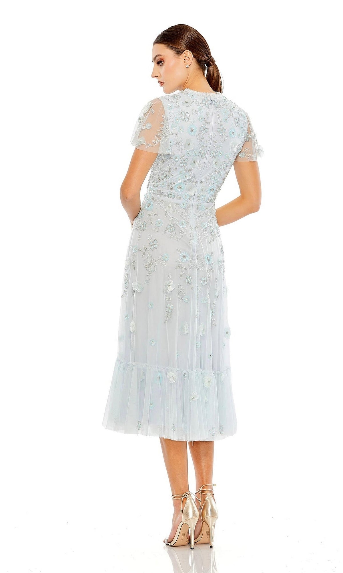 Woman wearing the Mac Duggal 9212 Floral Midi Wedding-Guest Dress with floral embroidery, knee-length and short-sleeve, seen from the back and styled with metallic high-heeled sandals.