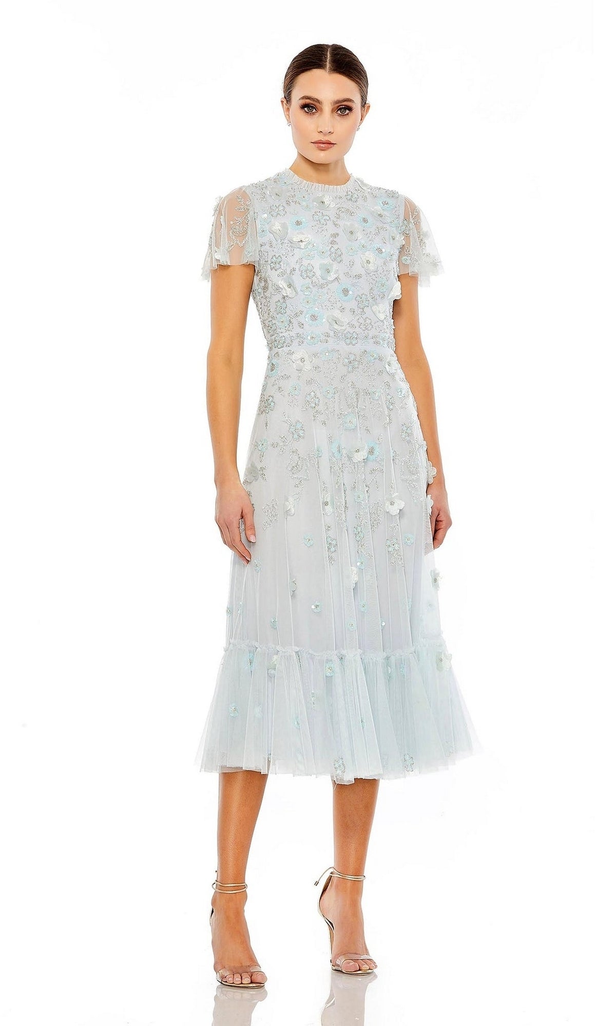 Woman wearing the Mac Duggal 9212 Floral Midi Wedding-Guest Dress—light blue with floral embroidery and sheer overlay—paired with nude heels, standing against a white background.