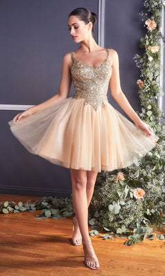 A woman in the Ballerina-Style Short Homecoming Dress 9239, featuring gold metallic-lace applique, stands indoors in strappy heels beside a floral arrangement.
