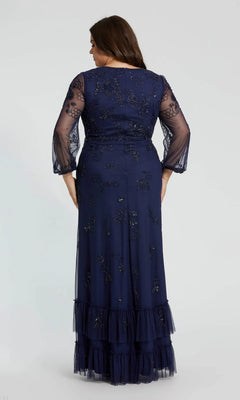 A woman stands with her back to the camera against a plain background, modeling the Long Plus-Size Formal Dress: Mac Duggal 9247—a navy gown featuring sheer embroidered sleeves and a ruffled hem for an elegant formal look.