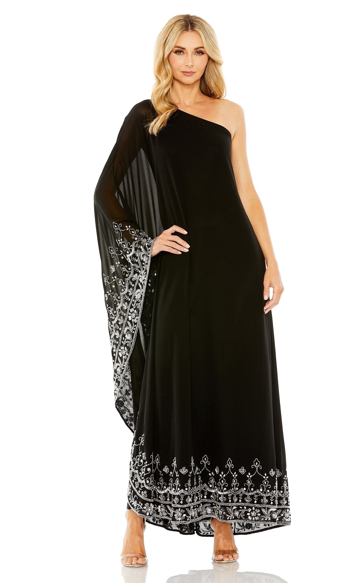 A woman models the Long Formal Dress 9251 by Mac Duggal—a black, one-shoulder gown with a sheer embellished cape sleeve and silver beaded hem—posing against a white background.