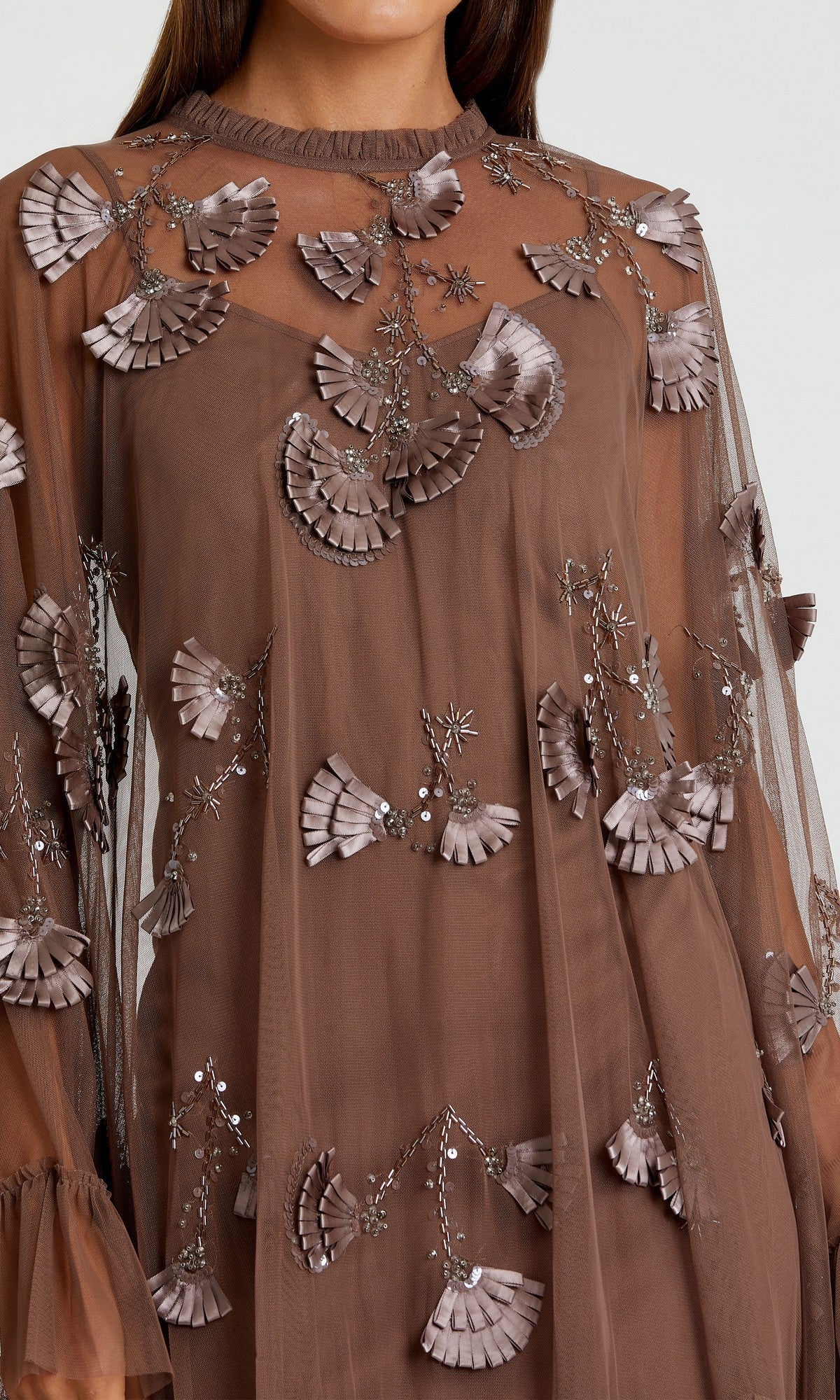 Woman wearing a sheer brown Mac Duggal 9257 Long Sleeve Short Hoco Dress with three-dimensional floral appliqués and silver beaded embellishments.