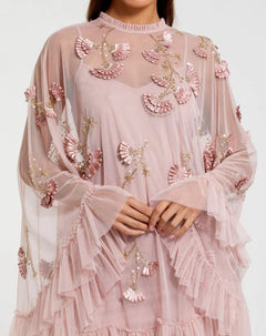 A person wearing the Mac Duggal 9257 Long Sleeve Short Hoco Dress in light pink, featuring sheer ruffles and floral appliqué, with hands folded at the waist.