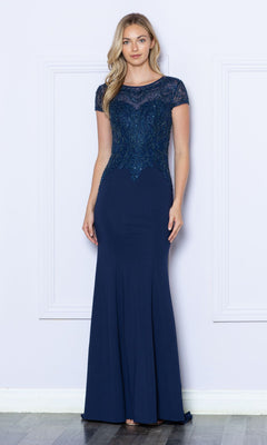 A woman stands indoors wearing the Beaded Short Sleeve Bodice Long Formal Dress 9320 in navy, featuring short sleeves and a bodice intricately embellished with sparkling beads.