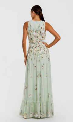Against a plain background, a woman stands with her back to the camera wearing the Mac Duggal 9334 Long Formal Dress—a sleeveless, light green gown adorned with floral embroidery and a sheer overlay.