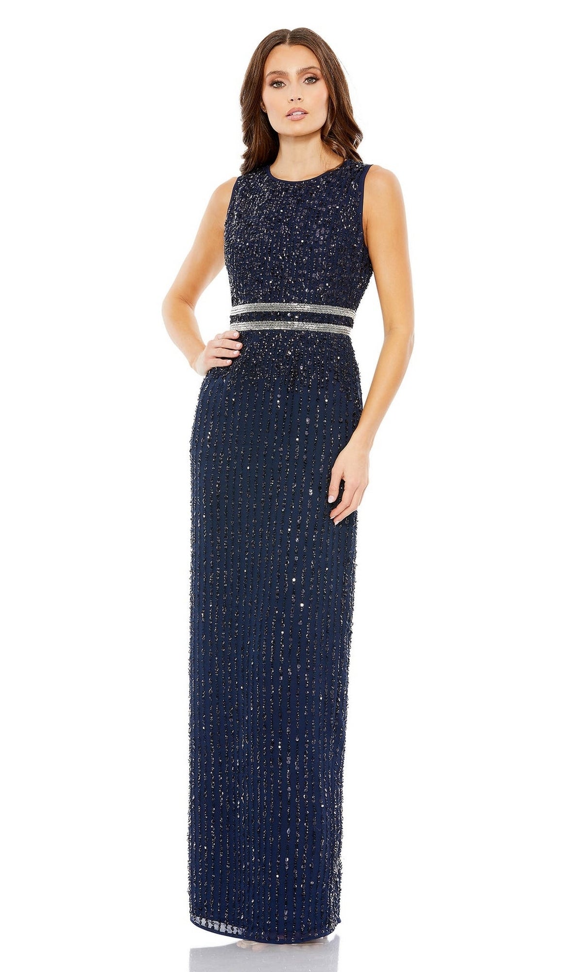 A woman in a sleeveless, floor-length Mac Duggal 93603 sequin formal dress with beaded vertical stripes and a silver waistband stands against a white background.