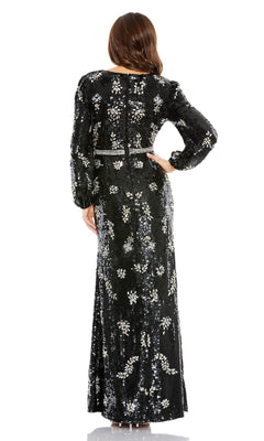 A woman stands facing away, wearing the Long Formal Dress 93616 by Mac Duggal—a black sequin evening gown with silver embellishments and long sleeves.