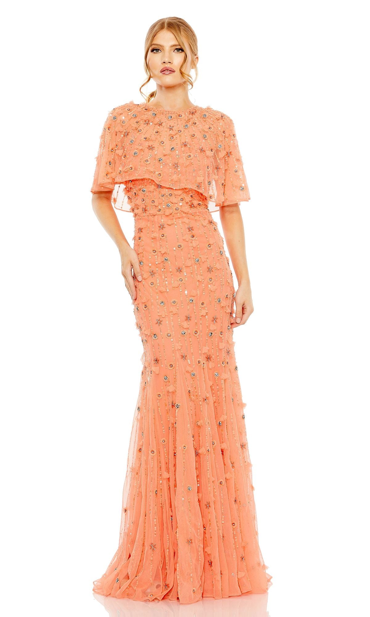 A woman in the Mac Duggal 93653 Beaded-Cape Long Formal Dress, a floor-length peach gown with floral embellishments and a layered capelet top, stands against a white background.