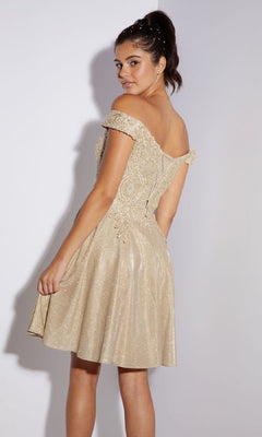 A woman stands facing backward, looking over her shoulder in the Eureka 9366 off-shoulder short glitter hoco dress, featuring shimmery beige fabric and delicate glitter-lace detailing.