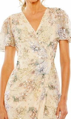 A woman wears the Mac Duggal 93749 Short Sleeve Beaded Formal Dress, featuring light floral sequins, flutter sleeves, a V-neckline, and a gathered waist for an effortlessly elegant look reminiscent of evening wear.