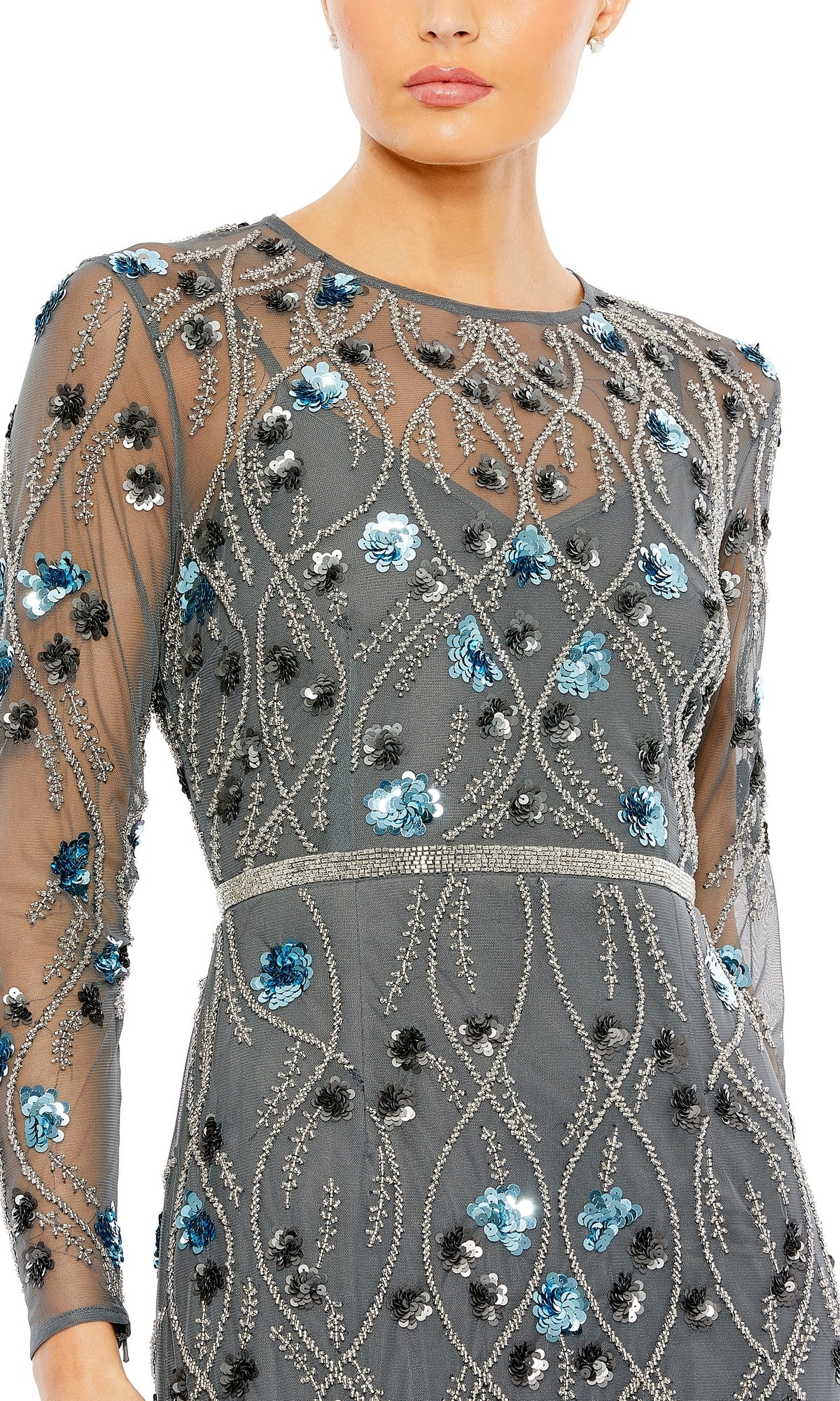 A person wearing the Mac Duggal Long Formal Dress 93772, a sheer gray gown with long sleeves and detailed silver, blue, and black floral embroidery.