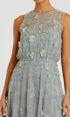 A woman wearing the Midi Party Dress: Mac Duggal 9380—a sleeveless, sage-green party dress adorned with beaded floral embroidery, delicate bead details, and a sheer neckline.