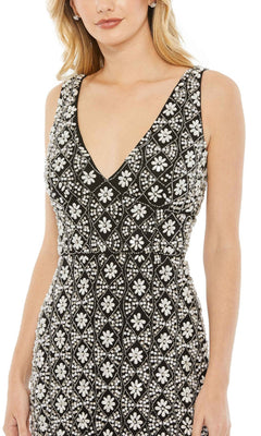 A woman wearing the Short Wedding Guest Dress 93807 by Mac Duggal, a fitted ankle-length black gown with a deep V-neckline and intricate white floral and geometric beaded patterns.