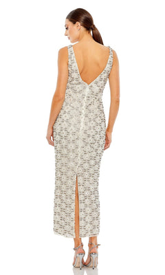 A woman wearing the Mac Duggal Short Wedding Guest Dress 93807—a semi-formal, sleeveless white dress with embellishments, deep V-back, and back slit—stands in high-heeled sandals.