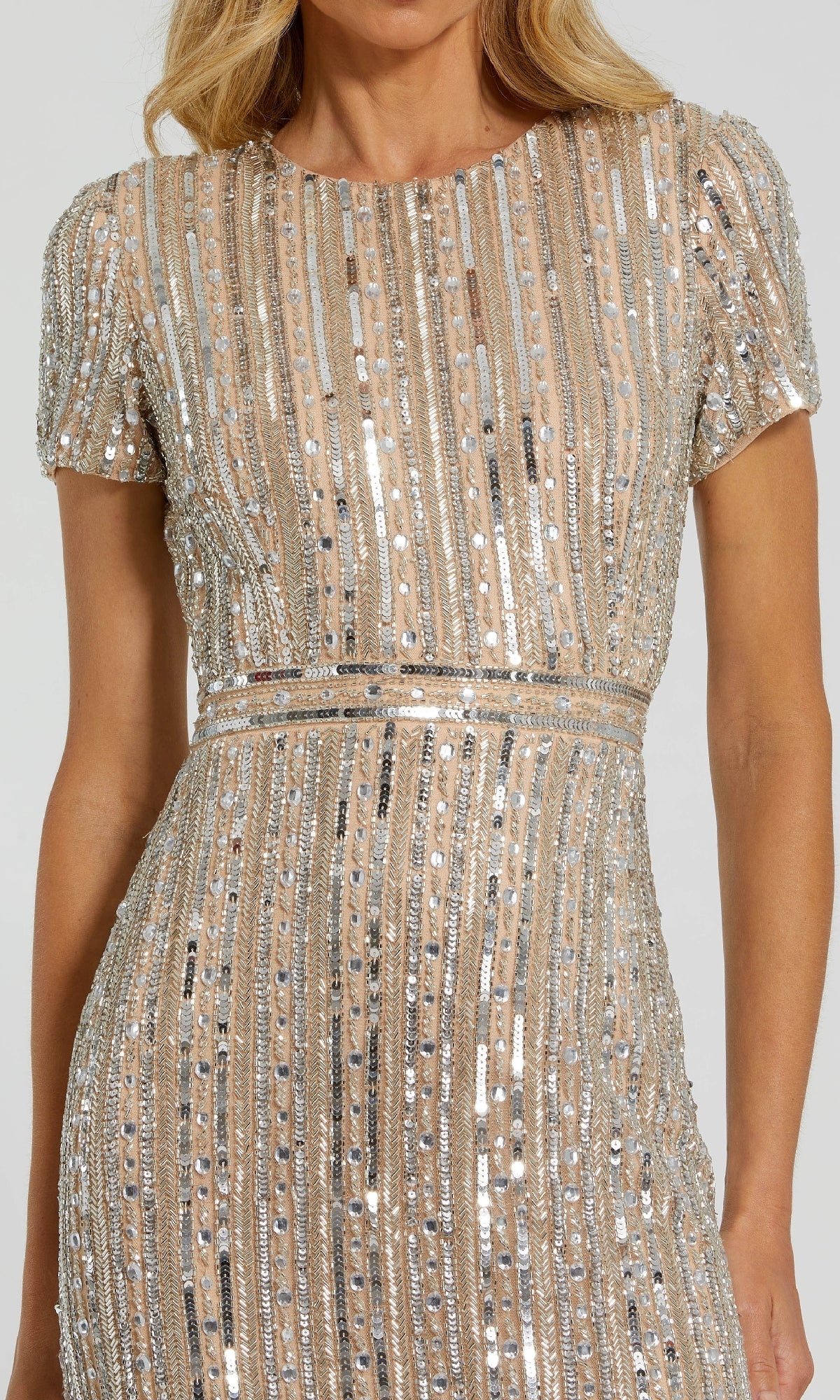 A woman wearing the Mac Duggal 93829 long formal dress, featuring short sleeves, a nude hue, and vertical rows of silver sequins with bead embellishments.