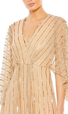 A person wearing the Mac Duggal 93841 Long Sequin A-Line Formal Dress in beige, featuring sheer elbow-length sleeves and gold sequin stripes.