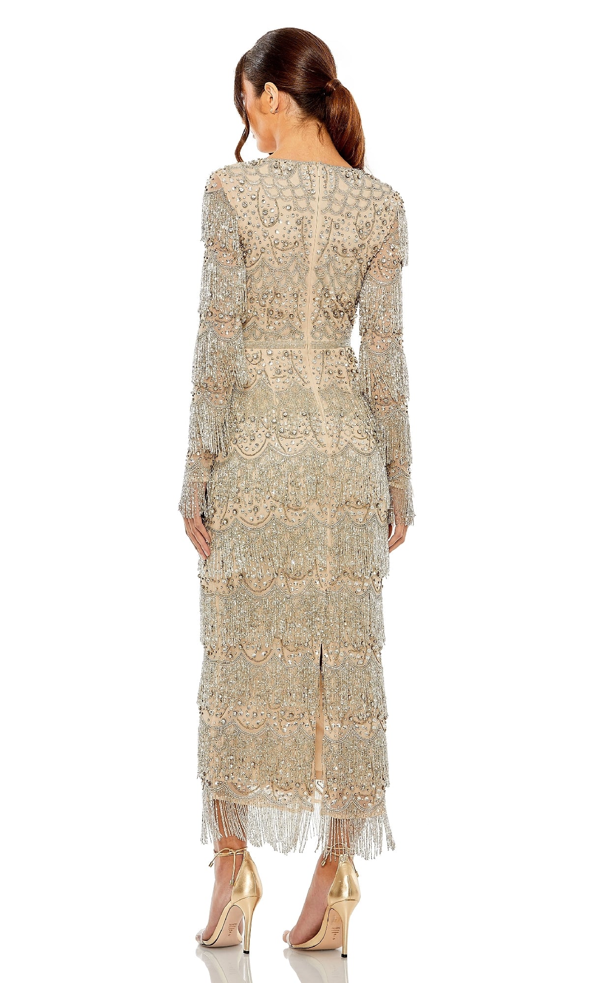 A woman in the Mac Duggal 93861 Long Sleeve Beaded Formal Dress poses in heels, showcasing its silver sheer fabric, intricate beadwork, and fringe details from the back against a white background.