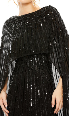 A person wearing the Mac Duggal 93869 Caped Long Sequin Formal Dress, a black gown with vertical sequin rows and draped, cape-like shoulder detailing.