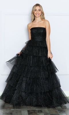 Smiling woman in the Strapless Long Tiered Glitter Prom Ball Gown 9386 in black, featuring a glittery tulle overlay and tiered skirt, stands against a white wall.