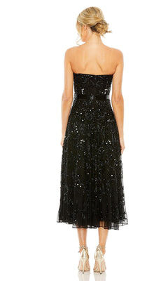 A blonde woman with her hair in an updo is shown from the back wearing the Mac Duggal 93898 strapless wedding guest dress, a black sequined midi party style, paired with gold high heels.