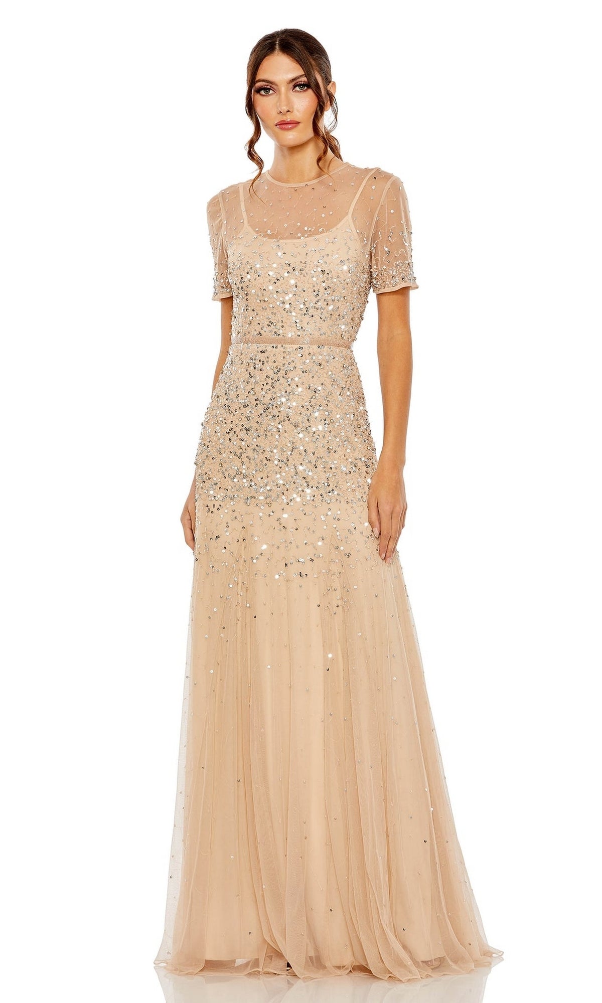 A woman models the Mac Duggal Sheer High-Neck Sequin Formal Dress 93909, a floor-length, short-sleeve gown with a sheer overlay and beaded waist, standing against a plain white background.