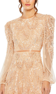 A woman wears the Mac Duggal 93930 Long Sleeve Beaded Formal Gown, a sheer nude evening dress adorned with sparkling sequin and bead accents in floral and geometric designs.