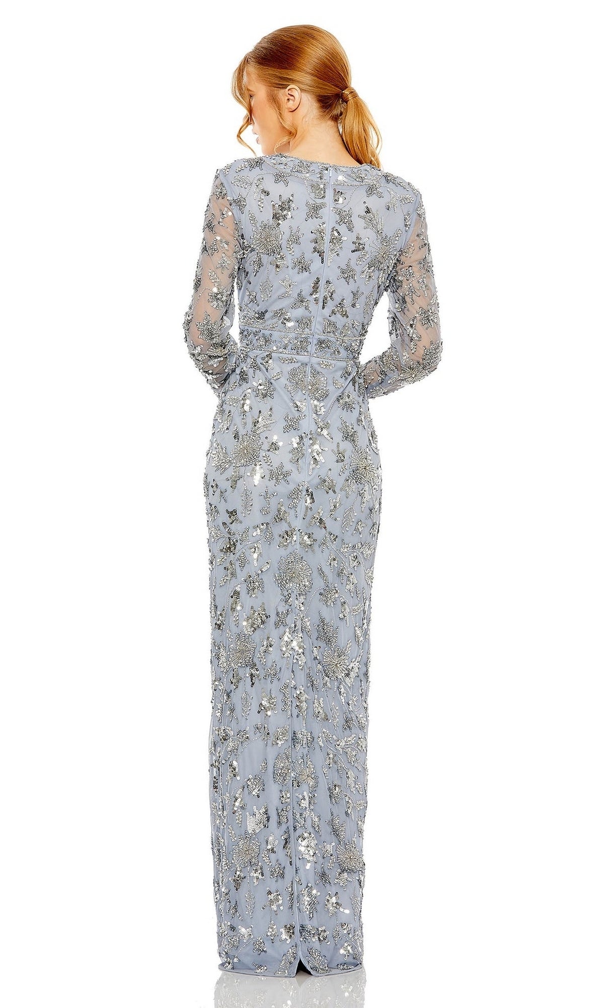 A red-haired woman in a ponytail models the Mac Duggal Slate Blue Sequin Formal Dress 93939, a long-sleeved, floor-length gown with silver embroidery and a sheath silhouette, shown from the back.