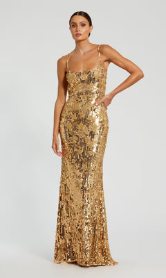 A woman stands against a plain light background wearing the Mac Duggal Long Formal Dress 93968—a sleeveless, floor-length gown with thin straps, crafted from shimmering gold sequins.
