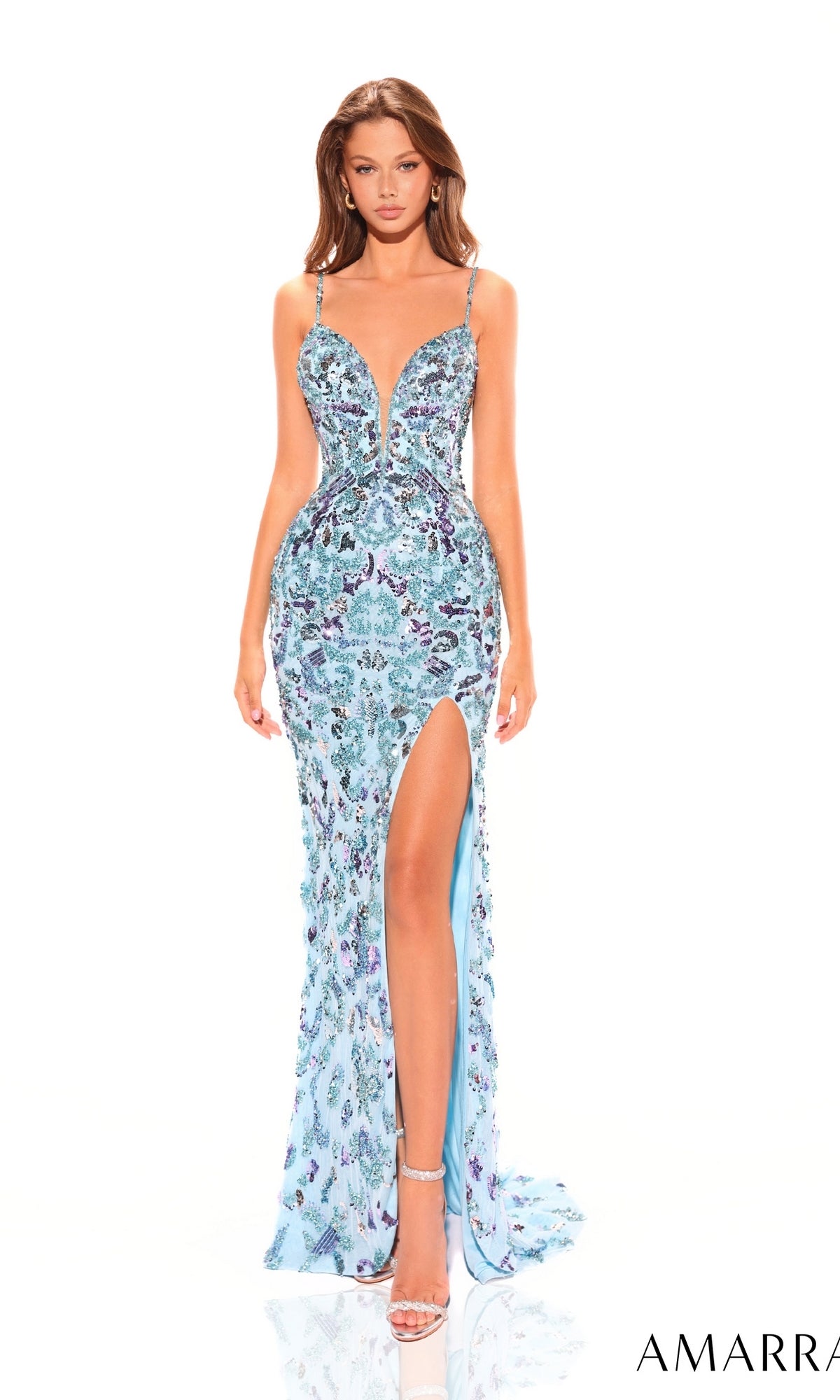 A woman models the Amarra Long Prom Dress 94003, a fitted light blue sequined gown featuring thin straps, a plunging sweetheart neckline, and a high slit, standing against a plain white background.