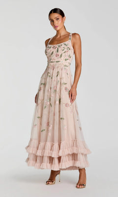 A woman wearing the Long Formal Dress: Mac Duggal 9402 in Porcelain, featuring delicate floral beaded embroidery, a ruffled hem, and elegant patterns, paired with gold open-toe heels and standing against a plain light background—a perfect party dress that exudes timeless elegance.
