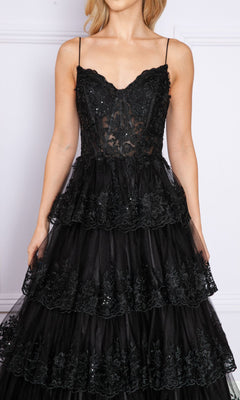 A woman stands against a light background wearing the Sheer-Bodice Long Ruffle Prom Ball Gown: Poly 9402, featuring an embroidered black sleeveless bodice with thin straps and tiered semi-sheer layers.