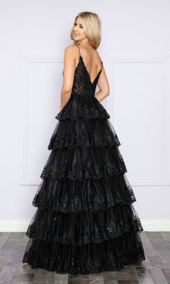 A woman stands facing away in a Sheer-Bodice Long Ruffle Prom Ball Gown: Poly 9402, showcasing its sleeveless design, embroidered-lace bodice, deep V-back, and layered ruffles in a room with light walls and wood floors.