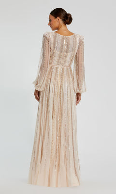 A woman faces away, wearing the Mac Duggal 94081—a long sleeve formal dress with sheer sleeves and vertical sequin embellishments. Her hair is styled in a low bun.