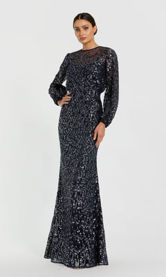 A woman poses against a plain light background wearing the Mac Duggal 94127 Long Sleeve Sequin Formal Dress, featuring a full-length silhouette, sequin accents, and a sheer neckline.