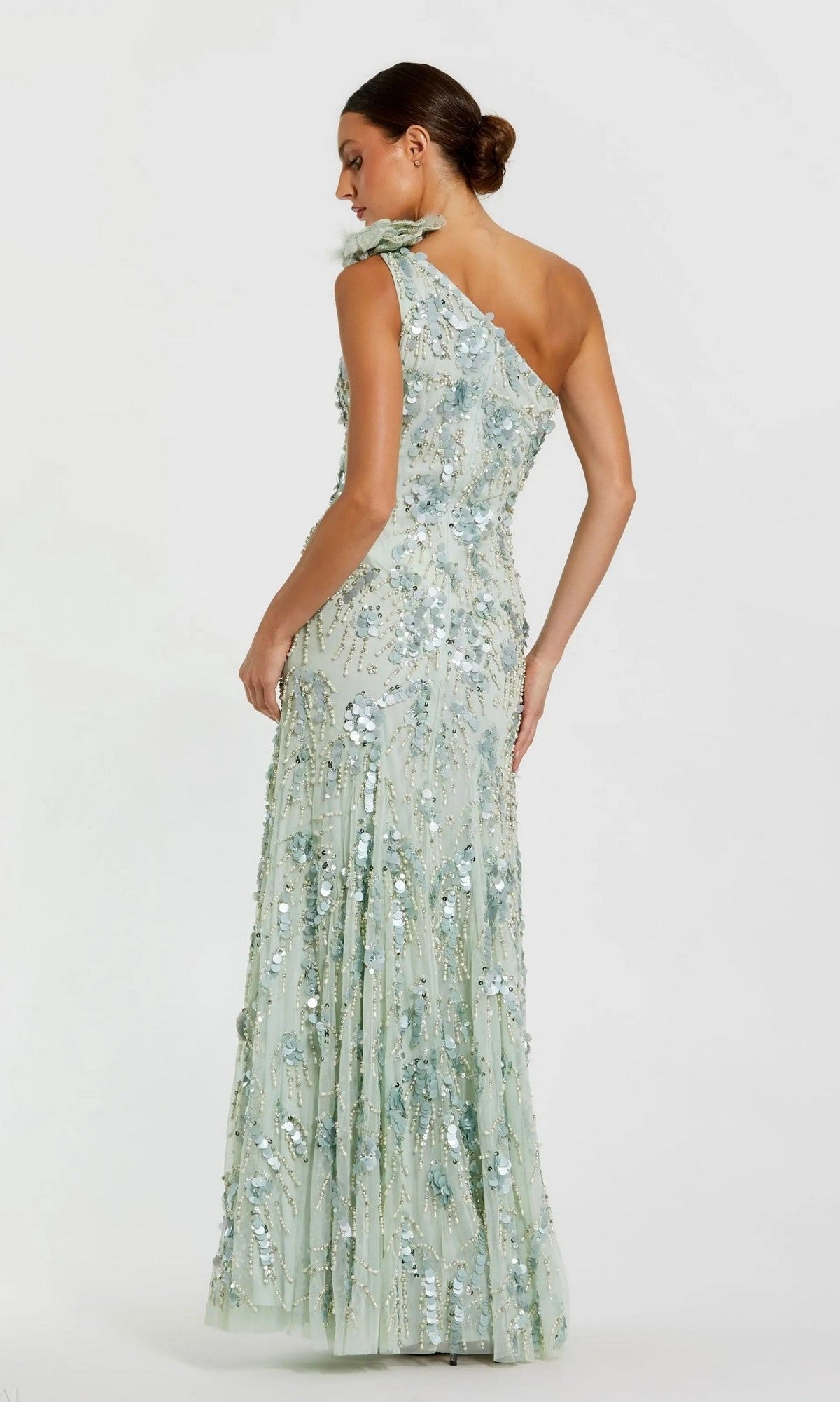 A woman poses with her back to the camera against a plain white background, wearing the Mac Duggal 94151 Long Formal Dress in pale blue—a one-shoulder, floor-length gown adorned with exquisite sequin beaded detailing.