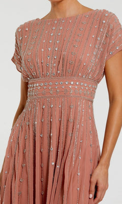 A woman wears the Midi Party Dress: Mac Duggal 94153, a pink gown embellished with silver beads and sequins in vertical and leaf patterns, exuding the elegance of a beaded midi dress.