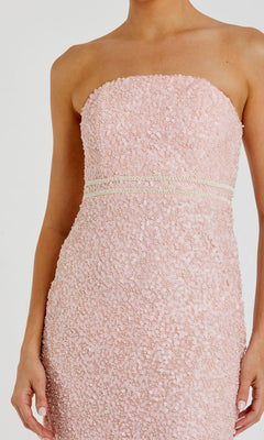 A woman wearing the Tea-Length Party Dress: Mac Duggal 94200—a fitted, strapless light pink dress adorned with pearls, textured sequin detailing, and two horizontal decorative bands at the waist.