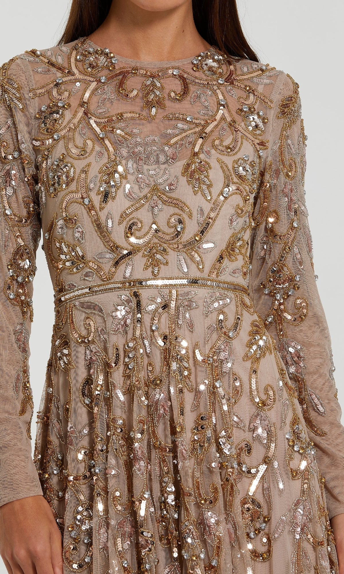 A close-up of a person wearing the Mac Duggal 94213: a long beaded gold formal dress with elaborate embroidery, sequins, sheer overlay, and long sleeves.