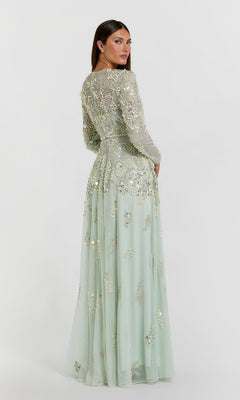 A woman is shown standing with her back to the camera against a plain white background, wearing the Mac Duggal 94215 long formal dress—a pale green, floor-length evening gown adorned with silver sequin and bead embellishments.